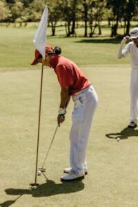 Two golfers enjoying a sunny day game, focusing on a precise putt on green.