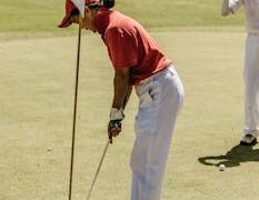 Two golfers enjoying a sunny day game, focusing on a precise putt on green.